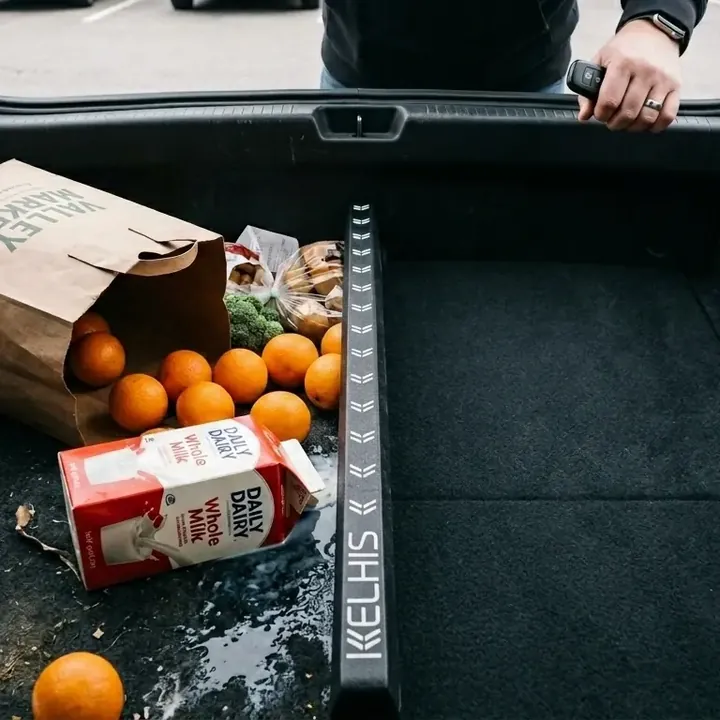 Arance sparse e un cartone di latte rovesciato nel bagagliaio di un’auto, accanto a un FlexiStick